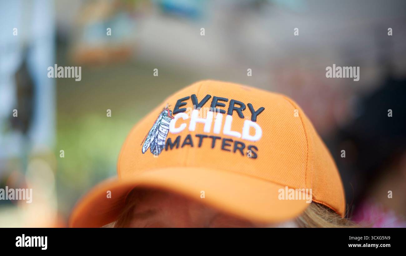 Eine Frau, die eine orange Baseballmütze trägt, mit jedem Kind drauf, während sie auf dem Nathan Phillips Square in Toronto City Hall während Truth and Reconciliat ist Stockfoto