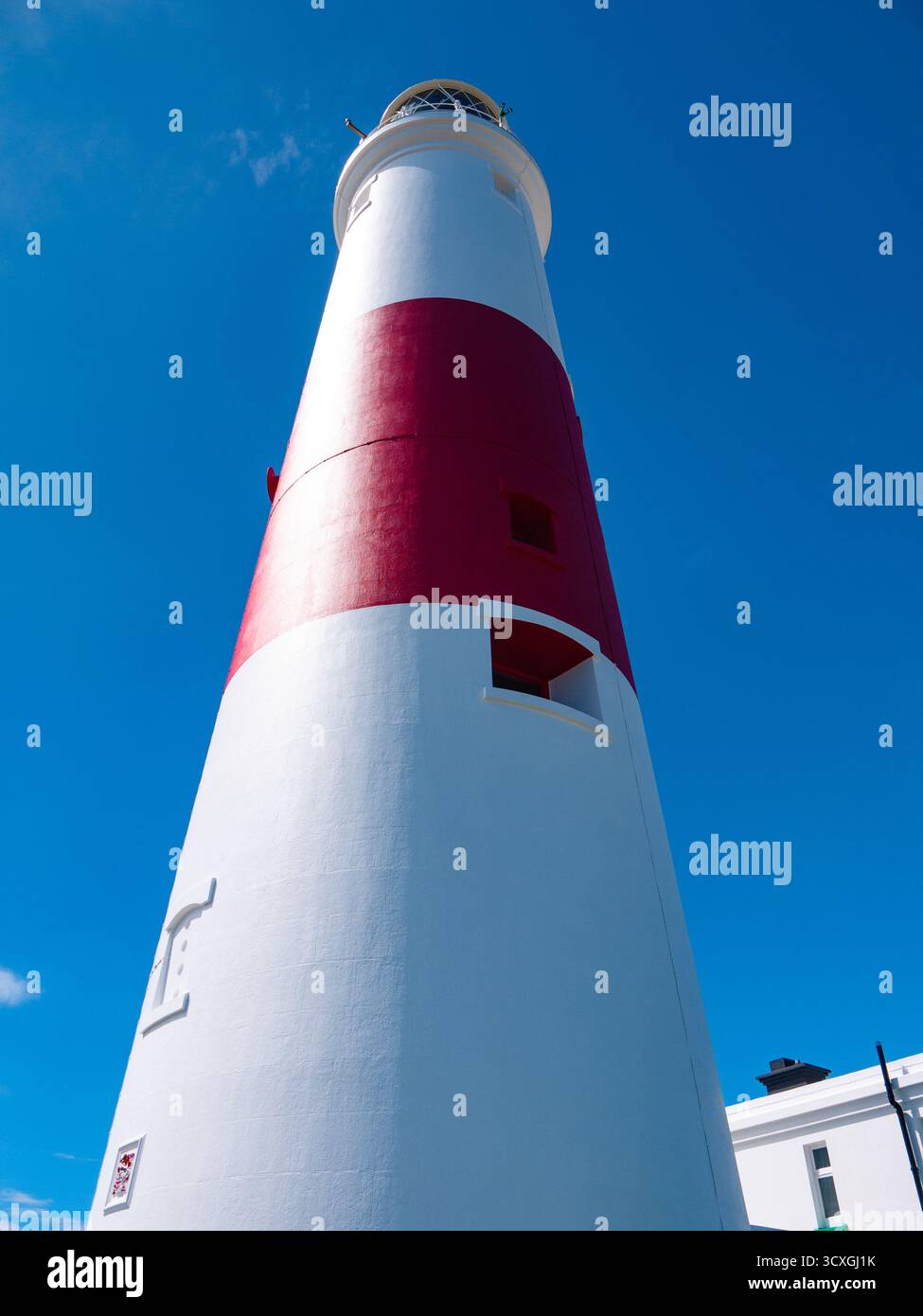 Weißer Leuchtturm mit rotem Streifen vor strahlend blauem Himmel in Dorset Stockfoto