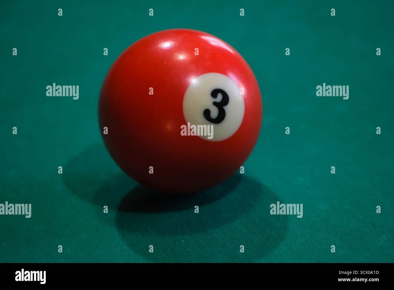 Rote 8-Kugel auf grünem Billardtisch unter sanftem Licht, Symbol für Fokus und Entscheidung im Billard- oder Spielstrategiekonzept Stockfoto