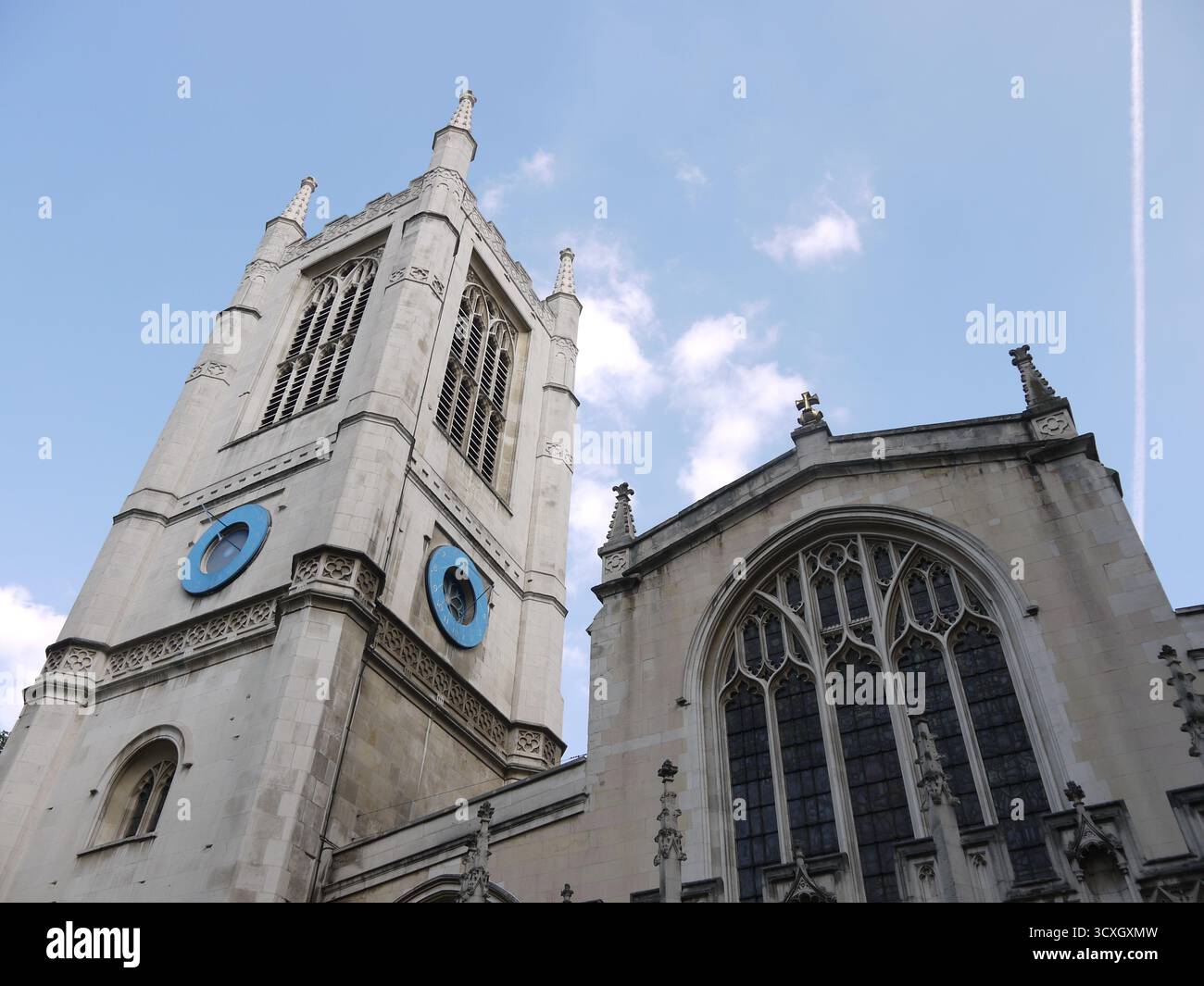 Historische Steinkirche mit Glockenturm und gotischen Fenstern vor blauem Himmel Stockfoto
