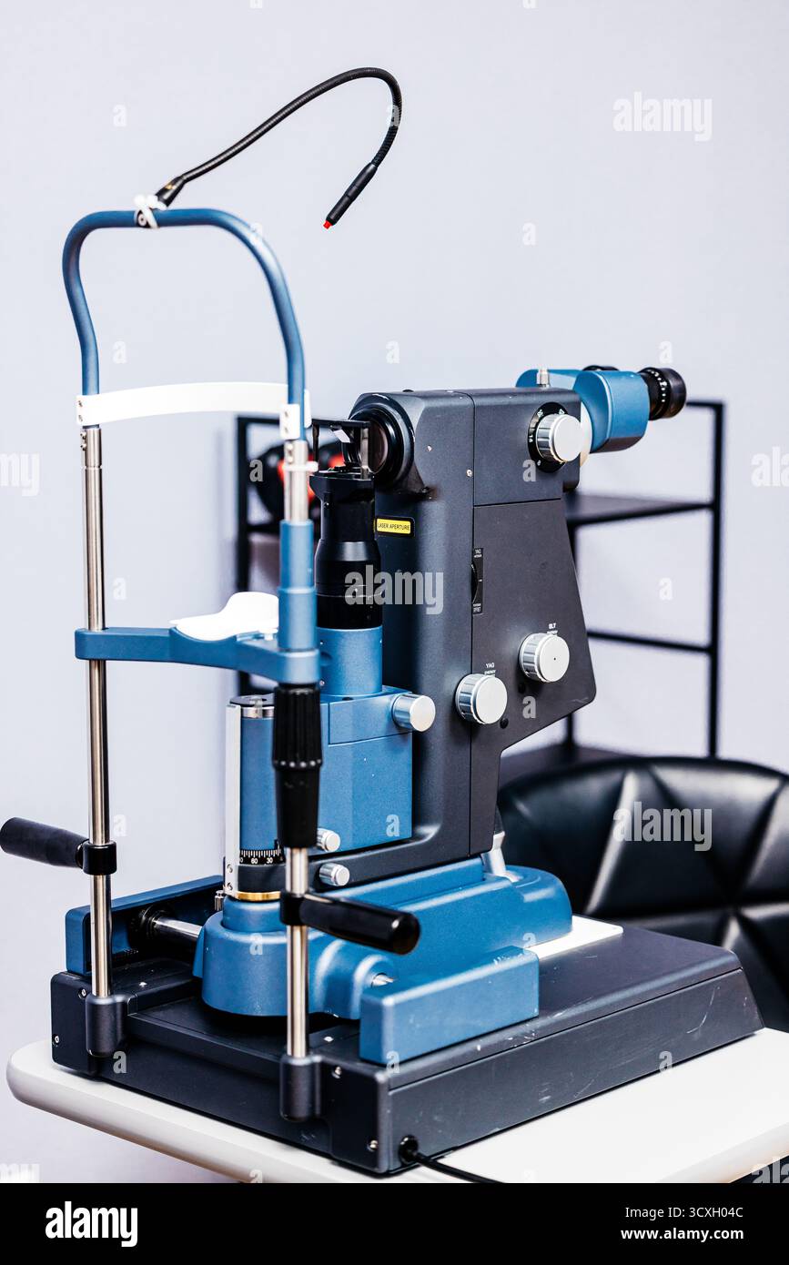 Das auf dem Untersuchungstisch positionierte Augenspaltgerät mit Spaltlampen hebt detaillierte Komponenten und eine professionelle Umgebung für eine gründliche Sehuntersuchung hervor Stockfoto