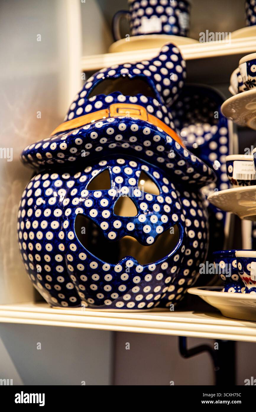 Einzigartiges Halloween-Dekor, handgemalte Keramikbuchse und Laterne auf dem Regal. Geschnitztes keramisches Kürbisgesicht Stockfoto