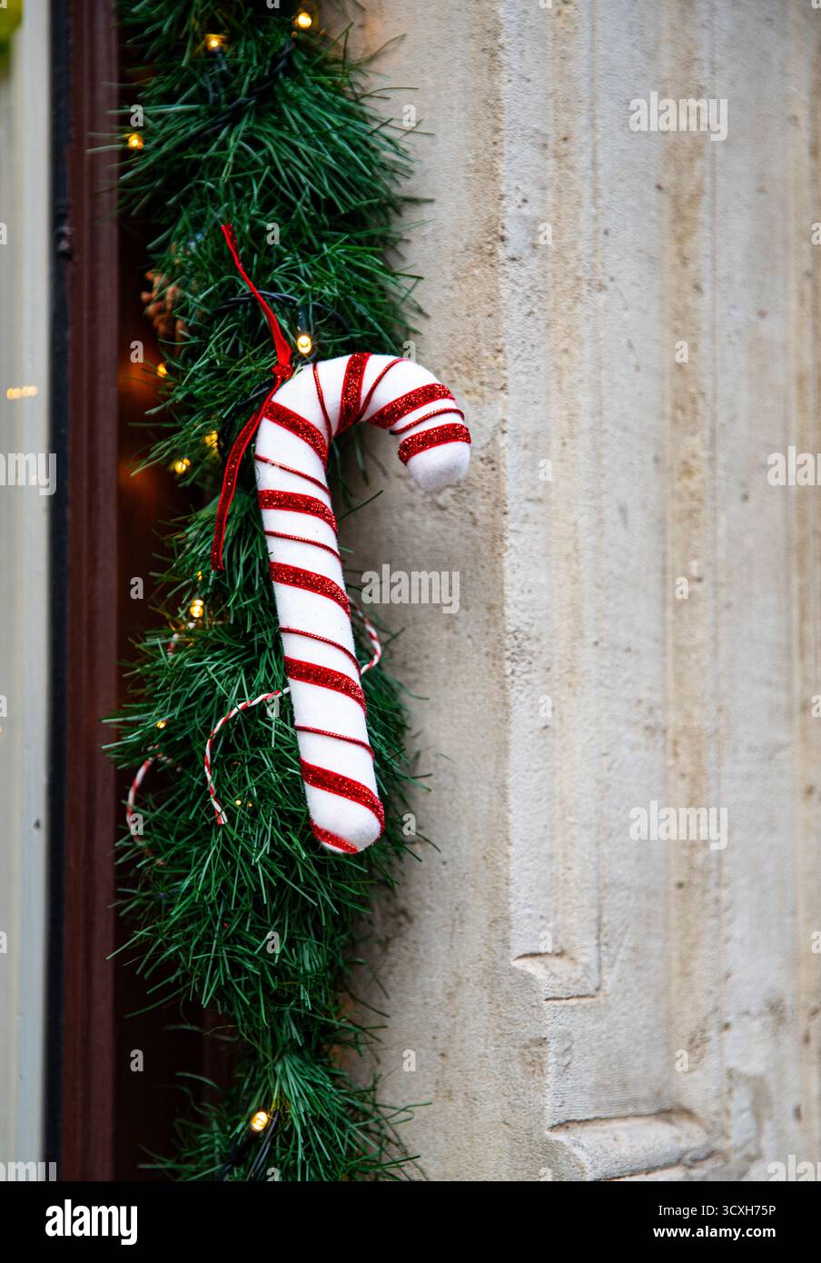 Traditionelle rot-weiß gestreifte Zuckerrohr-Ornamente, festliche Weihnachtsdekoration auf Weihnachtsgirlande Stockfoto