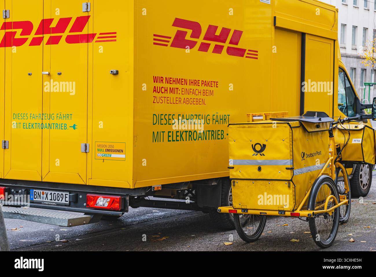 Gelber DHL-Lieferwagen mit Lieferfahrrad der Deutschen Post davor geparkt Stockfoto