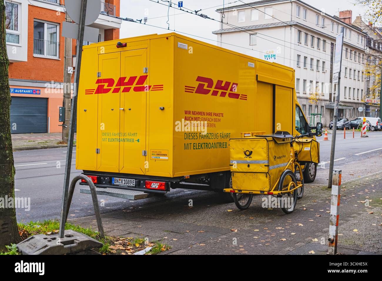 Gelber DHL-Lieferwagen mit Lieferfahrrad der Deutschen Post davor geparkt Stockfoto