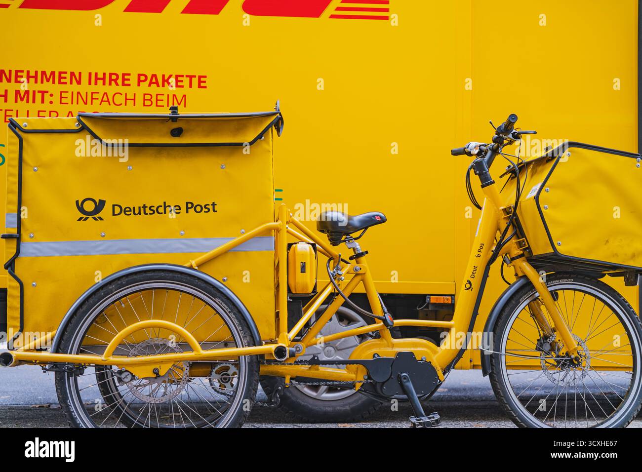 Nahaufnahme eines gelben DHL-Lieferwagens mit dem davor geparkten Lieferfahrrad der Deutschen Post Stockfoto