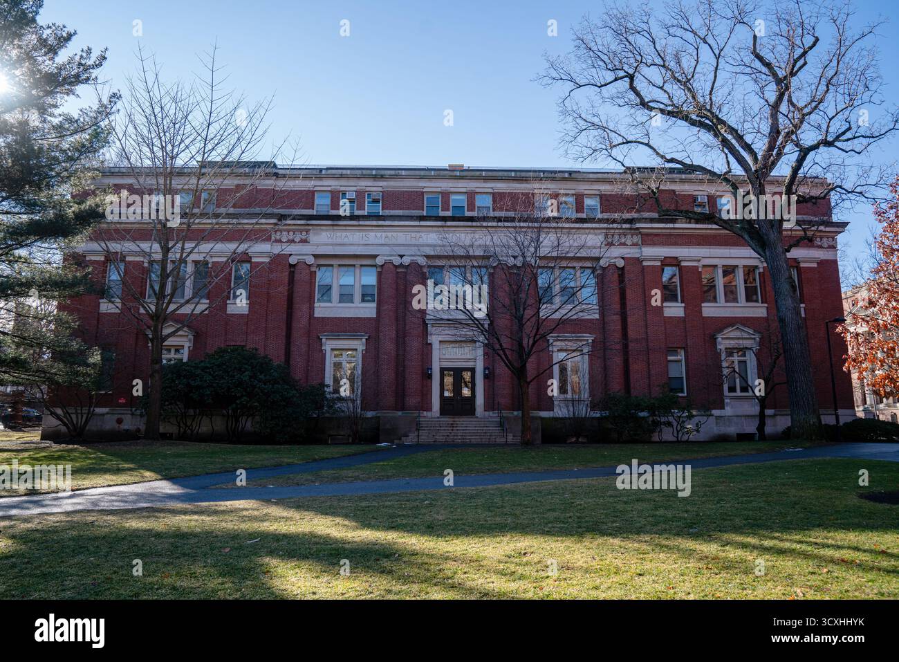Die Emerson Hall an der Harvard University steht unter einem klaren Winterhimmel mit roter Backsteinfassade und klassischen Säulen, die von Nachmittagslicht beleuchtet werden Stockfoto