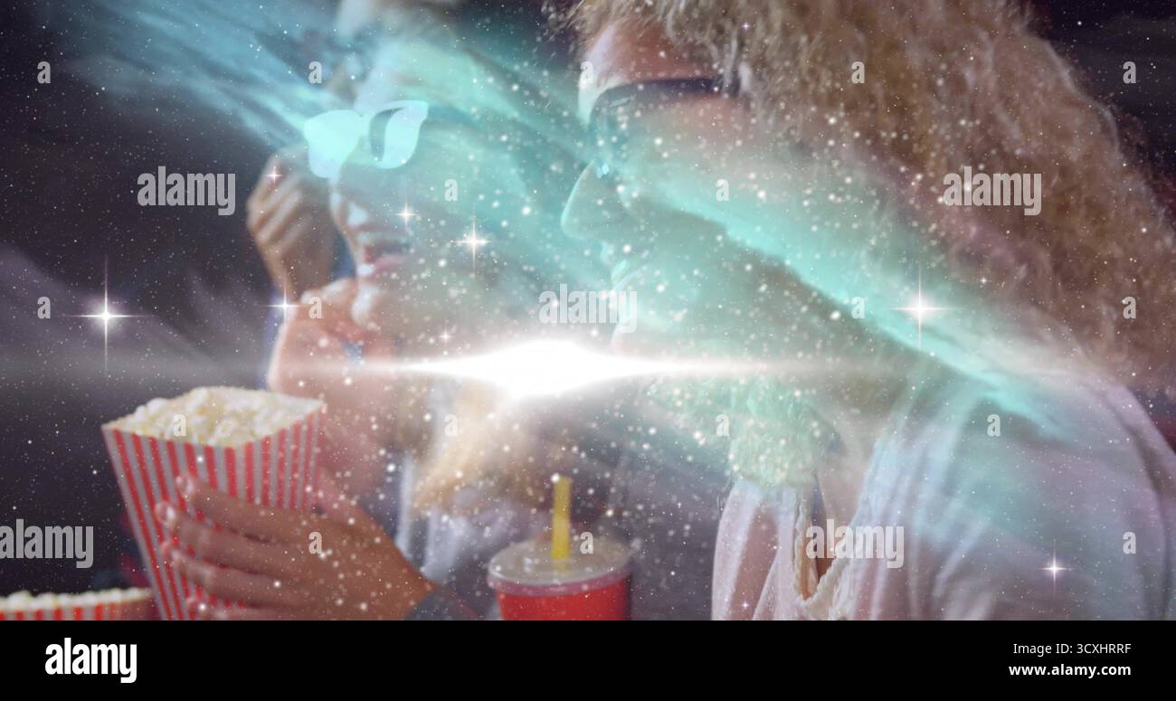 Popcorn in der Hand, rote Tasse, zwei Frauen mit 3D-Brille, die im Theater unter kosmischem Licht Filme sehen Stockfoto