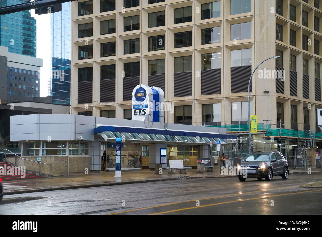 Ein Volkswagen SUV fährt am Eingang des 100 Street Edmonton Transit System (ETS) Bahnhofs in der Innenstadt von Edmonton vorbei, hinter dem sich Bürotürme erheben Stockfoto