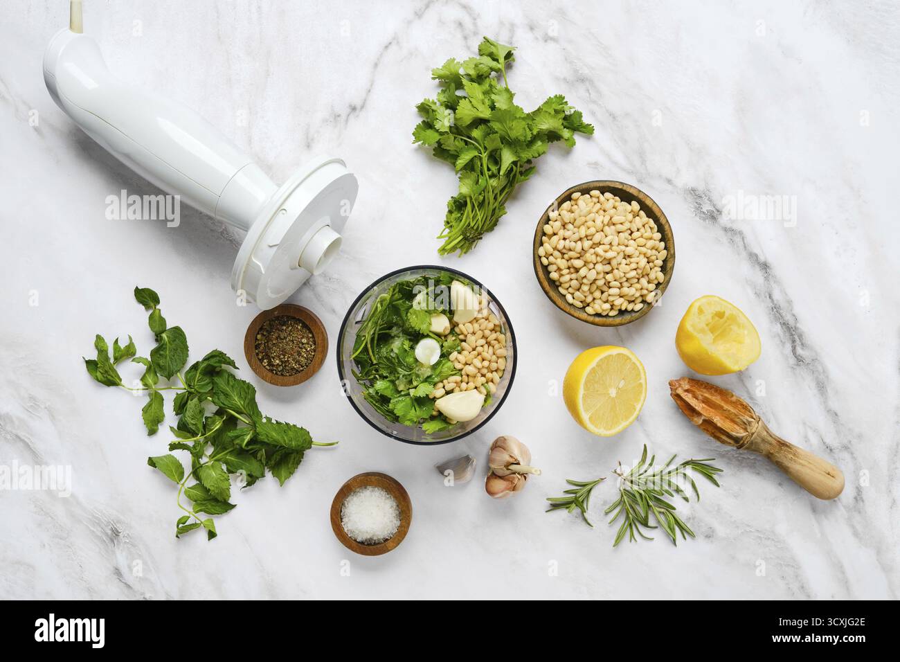 Frische Kräuter, Pinienkerne, Knoblauch und Zitrone in einer Schüssel zum Mixen. Diese Einstellung erfasst das Wesen der Zubereitung einer hausgemachten Sauce W Stockfoto