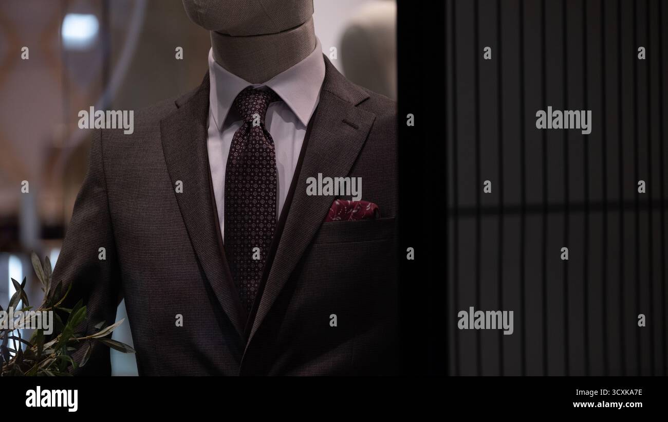 Nahaufnahme einer Männerpuppe in einem klassischen dunklen Anzug mit gemusterter Krawatte und Taschenquadrat, ausgestellt in einem Schaufenster. Das Foto nimmt die auf Stockfoto