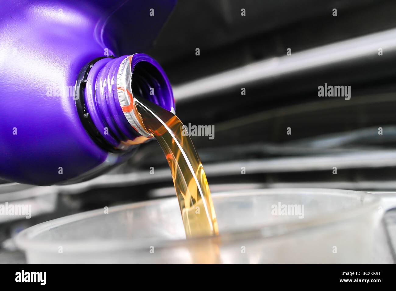 Motoröl wird aus der Flasche in den Behälter gegossen, Nahaufnahme des goldenen Schmierstoffflusses, Fahrzeugwartungskonzept mit Motorölwechsel, Auto se Stockfoto