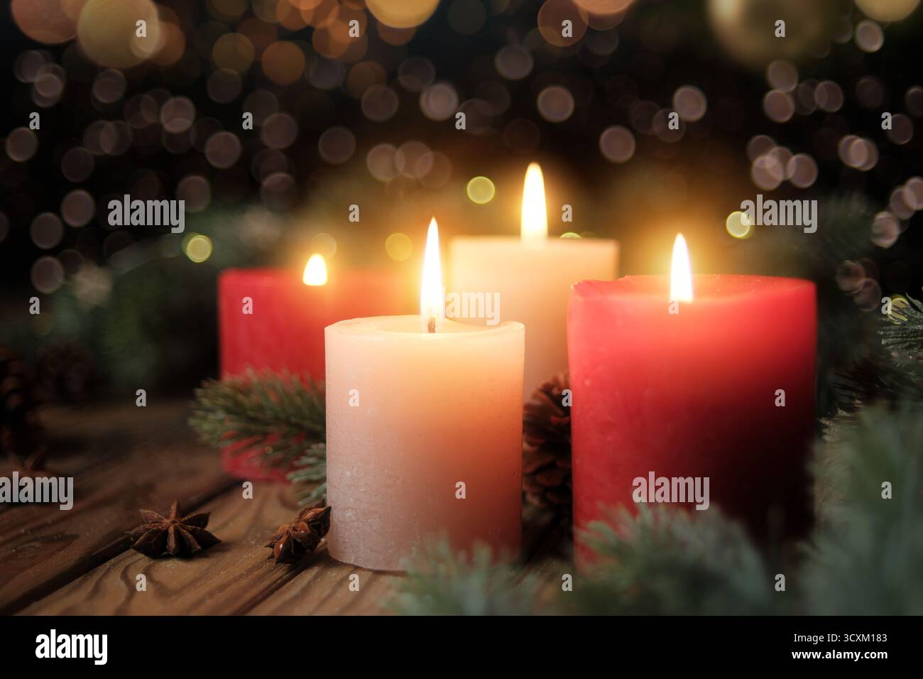 Vier brennende Kerzen mit dunklem, verschwommenem Hintergrund. Beschauliche Weihnachtsstimmung mit Adventskerzen, Tannenzweigen und Lichtern Stockfoto