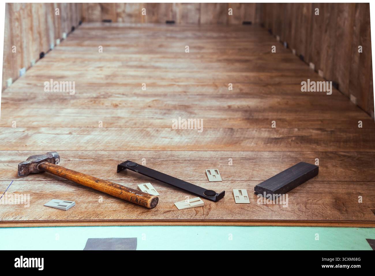 Die Verlegung von Laminatböden auf die Loggia. Das Laminat-Verlegewerkzeug liegt oben auf dem im Raum installierten Laminat Stockfoto