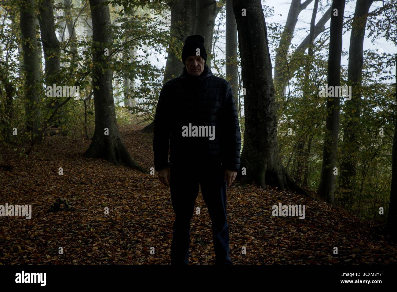 Gruseliger Mann, der vor dir steht und dich auf einem Wanderweg in dunkler Waldszene ansieht, Stalker folgt dir, gruselige Szene halloween Stockfoto