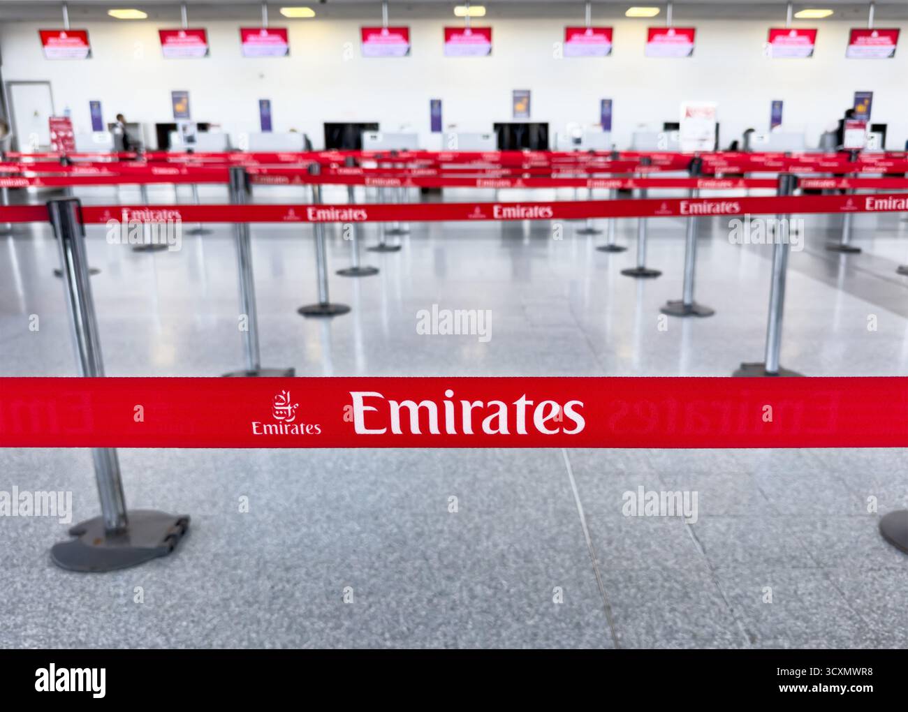 Leerer Emirates Check-in-Bereich an einem Flughafen mit roten Barrieren und Schildern mit dem Logo der Fluggesellschaft - Smartphone-aufgenommenes Stockfoto