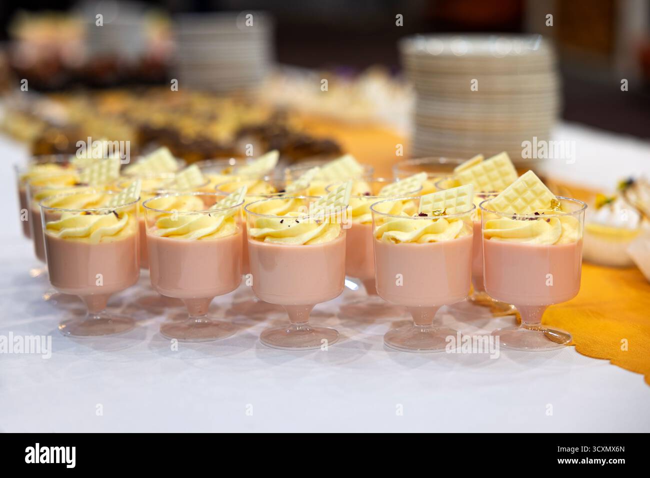 Rosafarbener Mousse-Kuchen mit Erdbeere, weißer Schokolade und Eclairs aus Glas auf dem Tisch Stockfoto