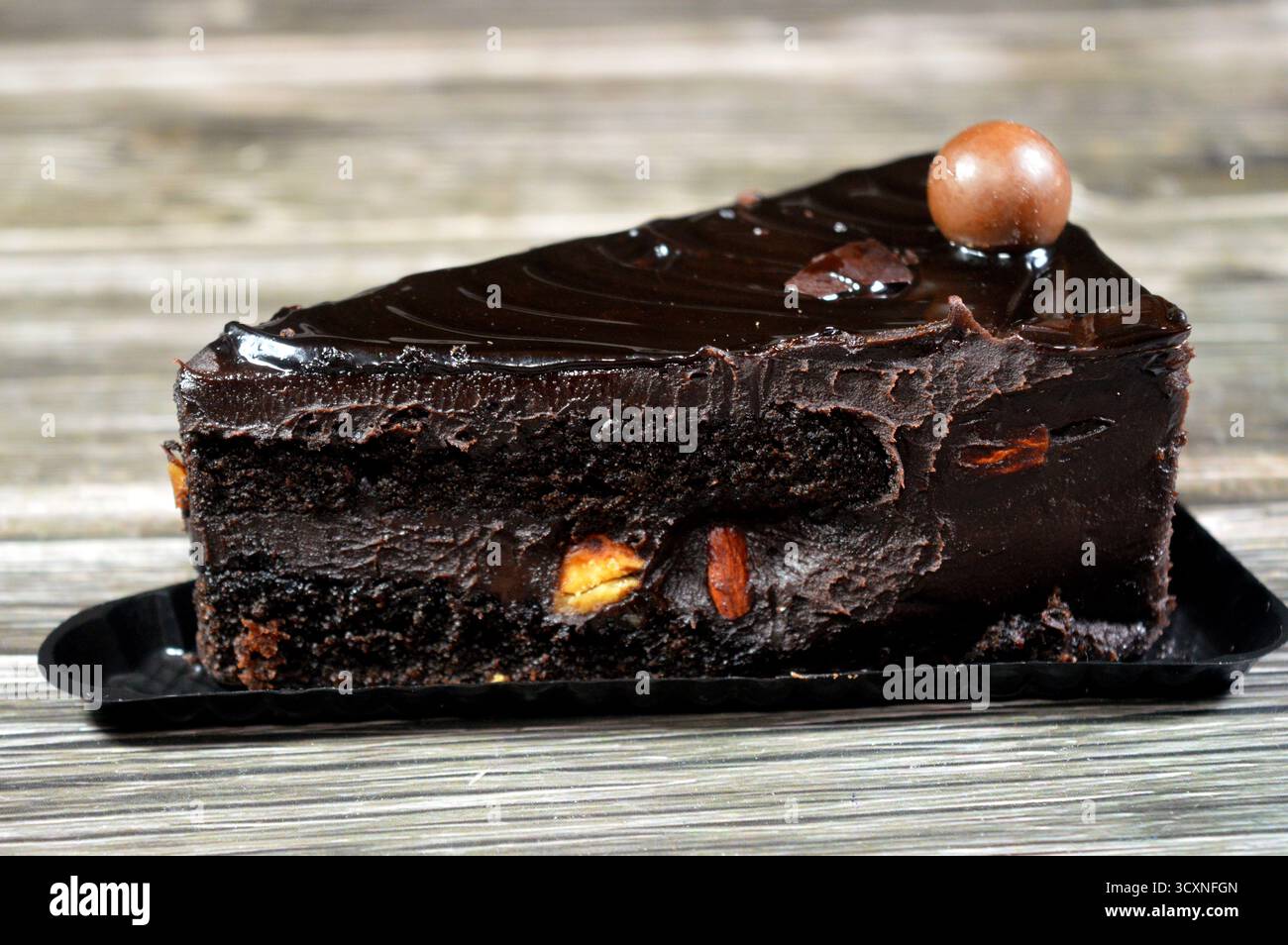 Fudge Cake Slice mit einer Schokoladenkugel, ein Schokoladenkuchen mit einer Konsistenz, einem Geschmack oder einem Reichtum, der an Fudge erinnert, ein mit mel aromatisierter Kuchen Stockfoto