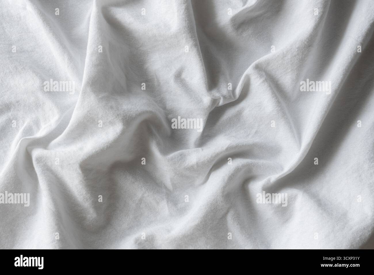 Weißer Stoffhintergrund mit weichen wellenförmigen Falten und sanfter Textur, ideal für minimalistisches Design, Mode oder Innenpräsentation. Stockfoto