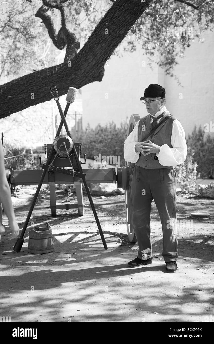 Schwarz-weiß-Foto eines männlichen Reenactors neben einer Kanone während eines lebendigen Geschichtsprogramms in der Alamo Mission in Texas Stockfoto