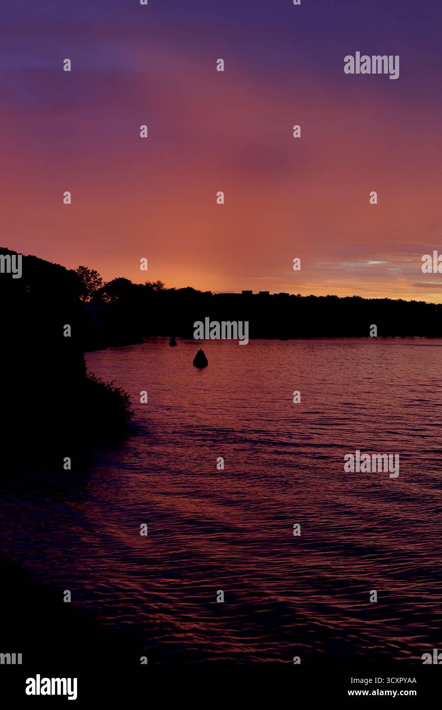 Farbenfroher Abenddämmerhimmel über dem Amsterdam-Rijnkanaal mit Wasser und einer dunklen Baumgrenze, fotografiert in der Nähe von Nesciobrug in Amsterdam, Niederlande bei Dämmerung. Stockfoto Farbenfroher Abenddämmerhimmel über dem Amsterdam-Rijnkanaal mit Wasser und einer dunklen Baumgrenze, fotografiert in der Nähe von Nesciobrug in Amsterdam, Niederlande bei Dämmerung. Stockfoto