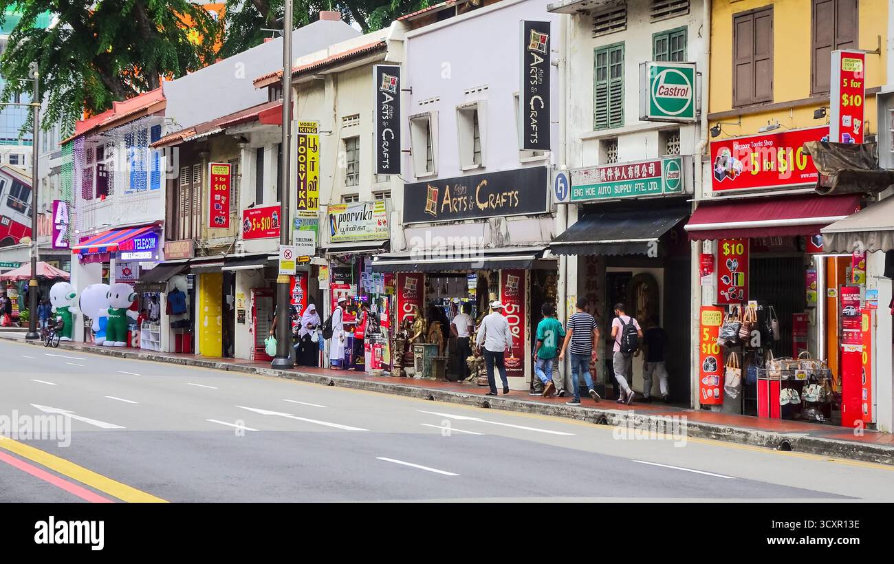 Blick auf die Straße in einem ethnischen Viertel in Singapur, mit kleinen bunten Gebäuden, lokalen Geschäften und einer lebhaften urbanen Atmosphäre. Stockfoto