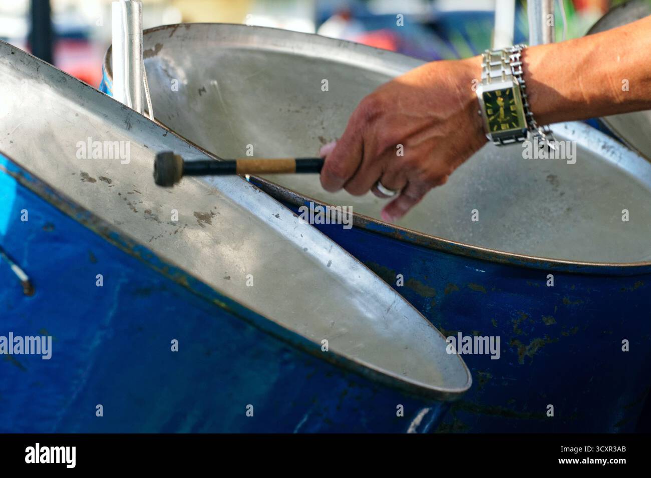 Ein Musiker spielt auf Stahltrommeln und erfüllt die Luft mit lebhaften karibischen Rhythmen bei einem Outdoor-Event, das die Zuhörer in ihren Bann zieht. Stockfoto