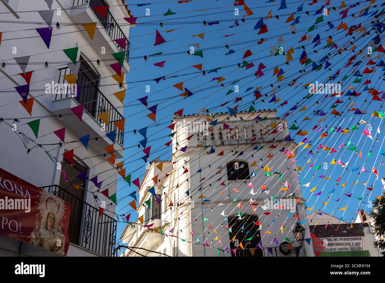 Farbenfrohe dreieckige Fahnen und Banner schmücken die Straßen während eines Dorffestes in Casares. Casares, Andalusien Spanien. 5. September 2025. Stockfoto