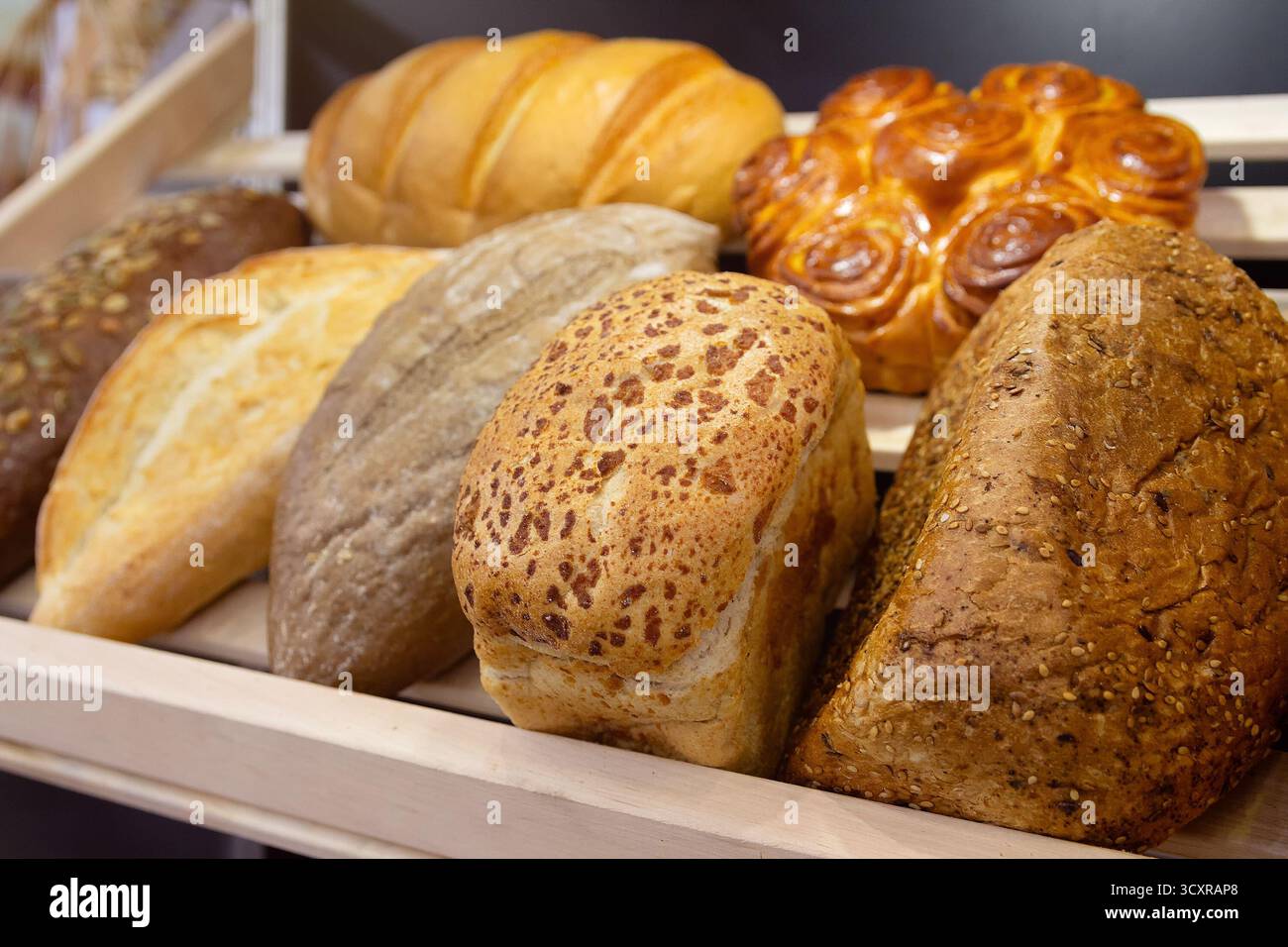 Auswahl an frisch gebackenem Brot auf Holzregalen Bäckerei Sauerteig. Essen Stockfoto