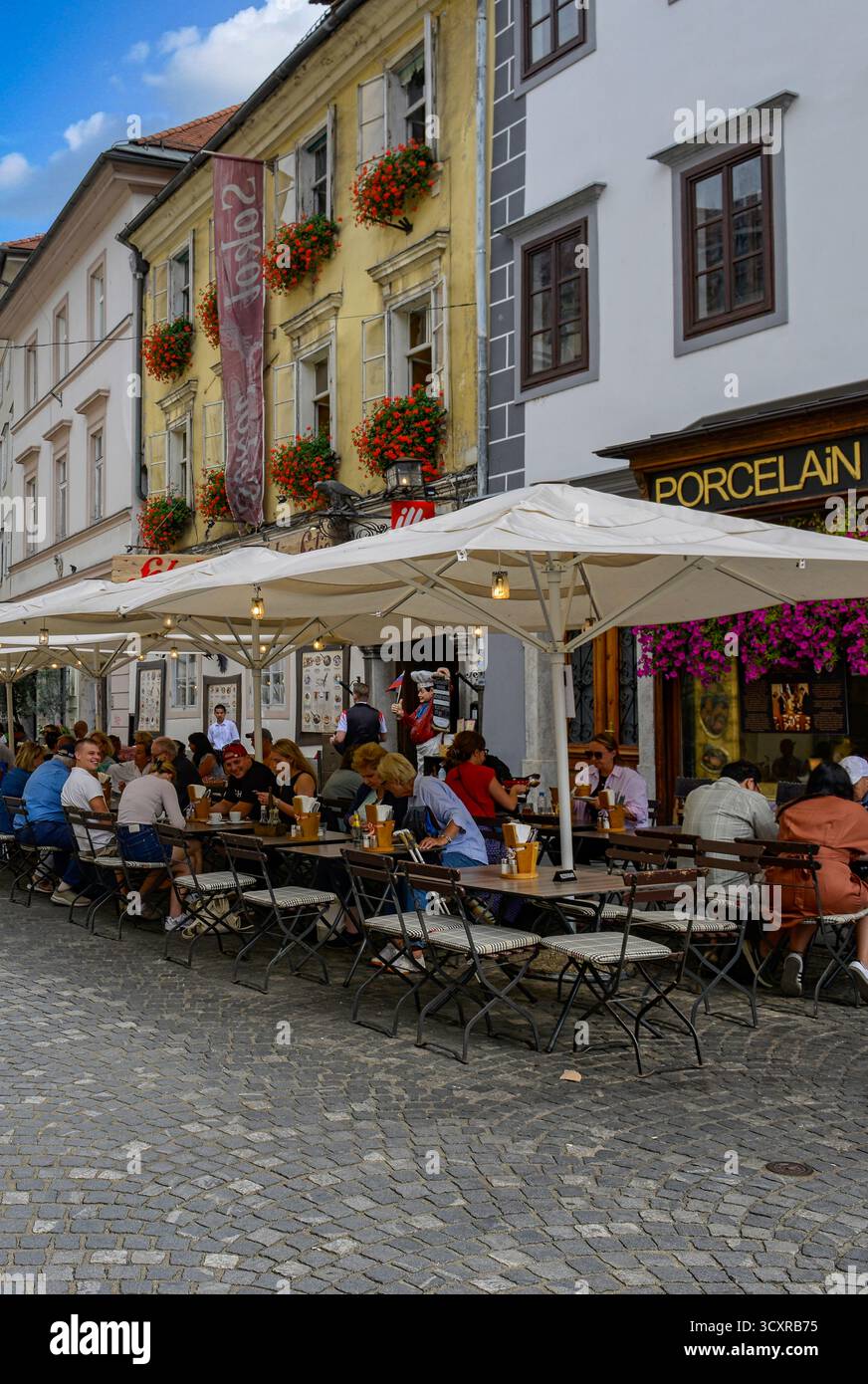 Gäste genießen das Essen und Trinken vor dem Porzellan Catbriyup Cafe auf der Ciril-Metodov trg in Ljubjana, Slowenien Stockfoto