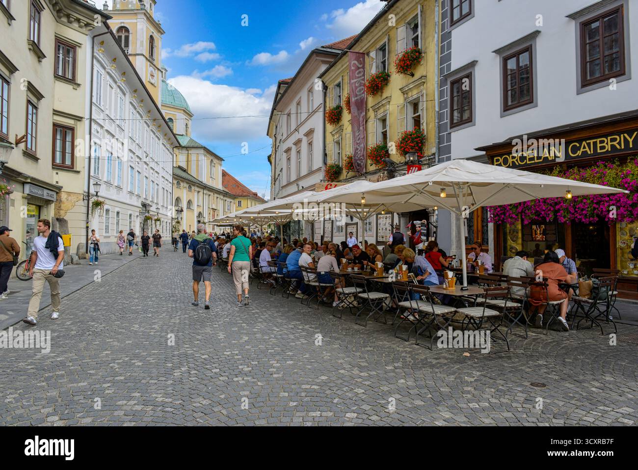 Gäste genießen das Essen und Trinken vor dem Porzellan Catbriyup Cafe auf der Ciril-Metodov trg in Ljubjana, Slowenien Stockfoto