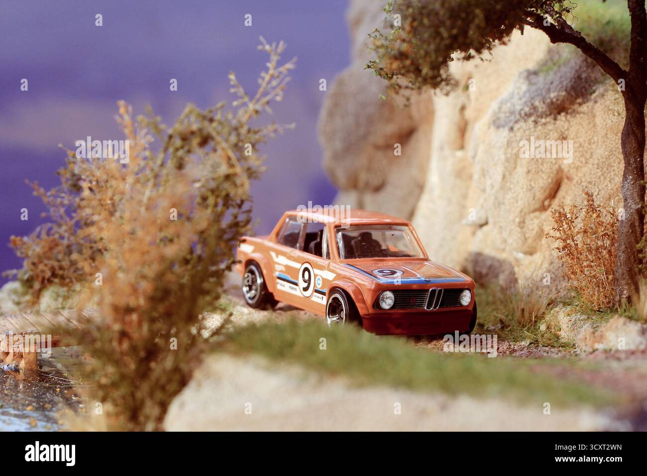 Detailreiches Miniatur-Diorama mit einem klassischen BMW 2002 Rennwagen aus dem Jahr 1969 in einer lebhaften Outdoor-Umgebung. Stockfoto