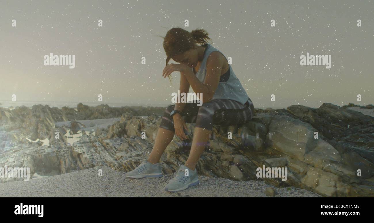 Eine ausgeruhsame, sportliche Frau, die sich an der Kiesküste nach vorne lehnt, mit Fitnessuhr und Laufschuhen Stockfoto
