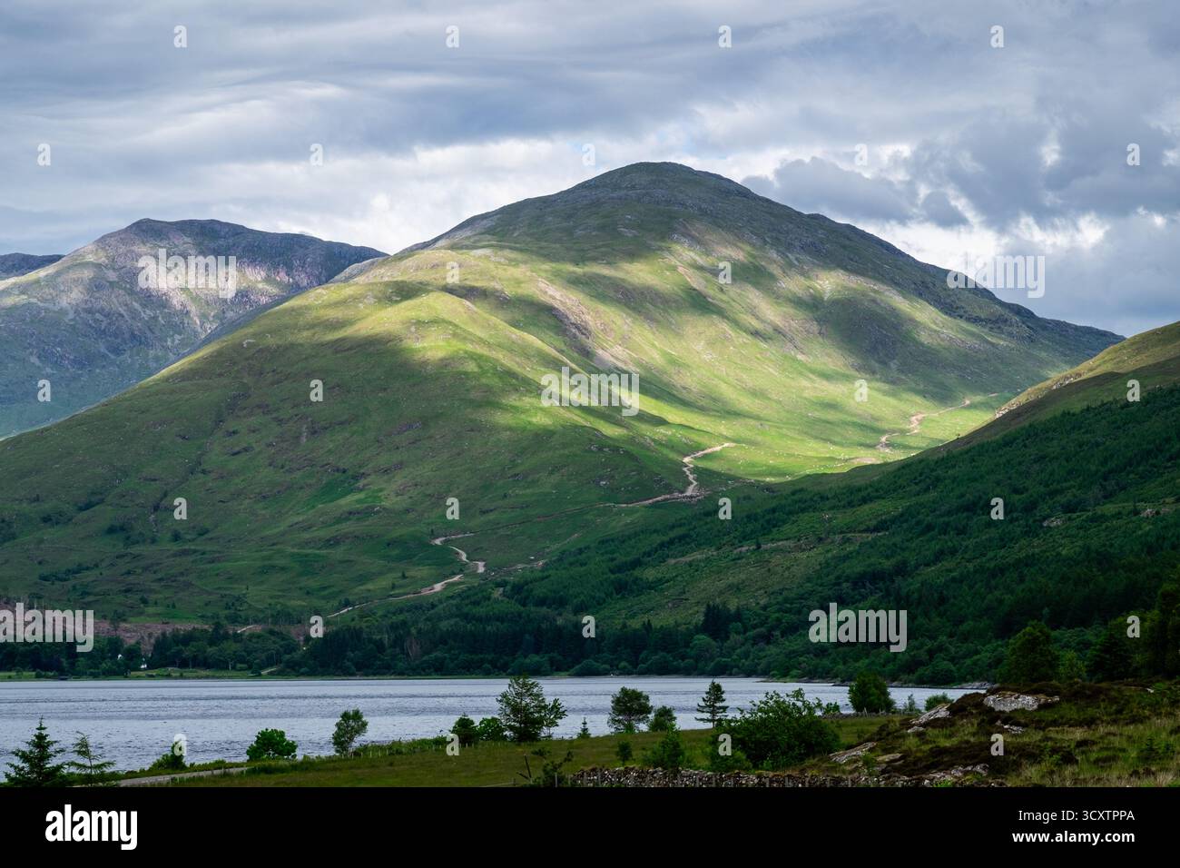 Sonnenlicht und Schatten über grünen Hügeln über Loch Creran in den schottischen Highlands Stockfoto