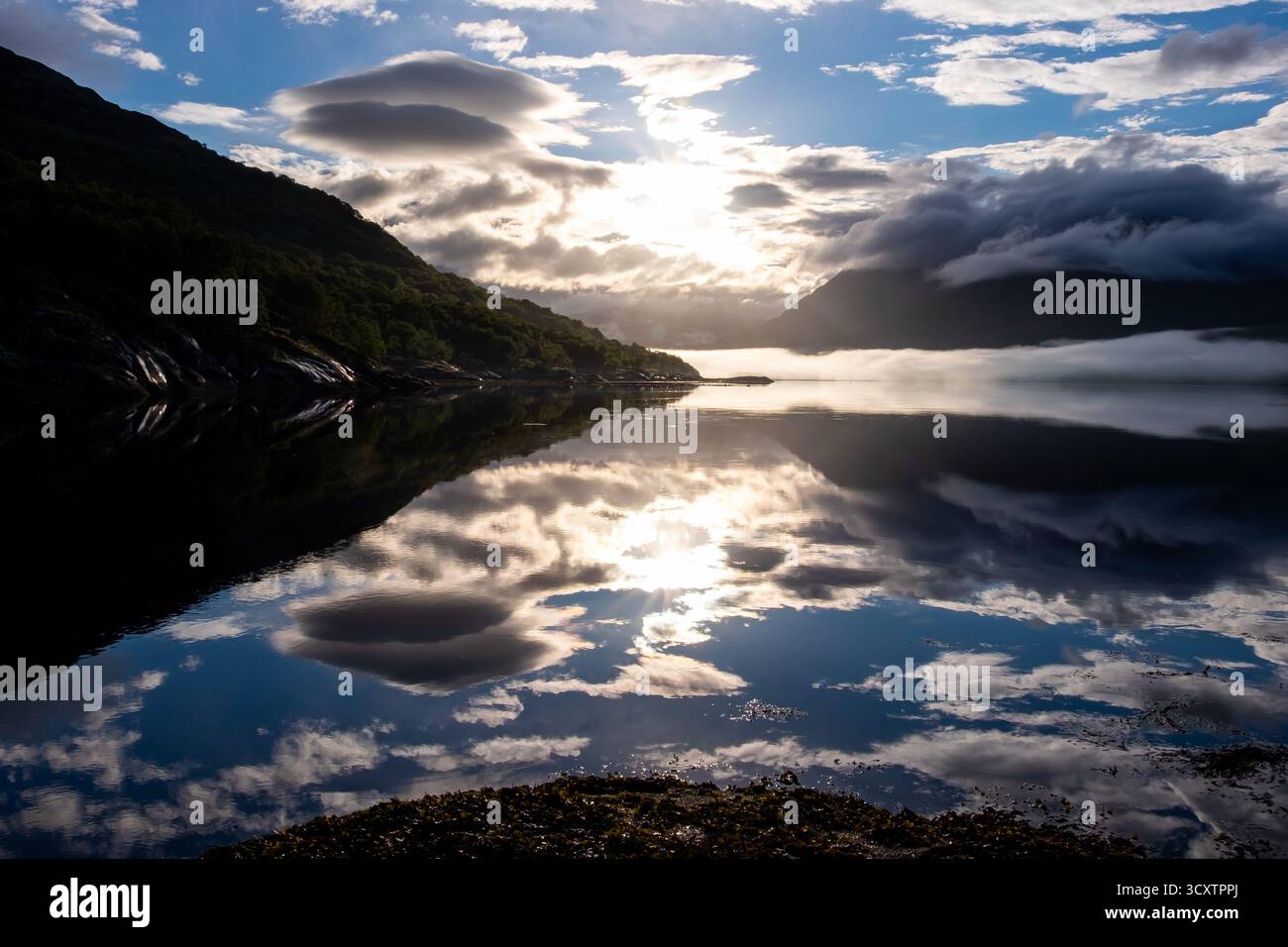 Sonnenaufgang Nebel und Reflexionen auf Loch Creran mit Bergen und Wolken Stockfoto