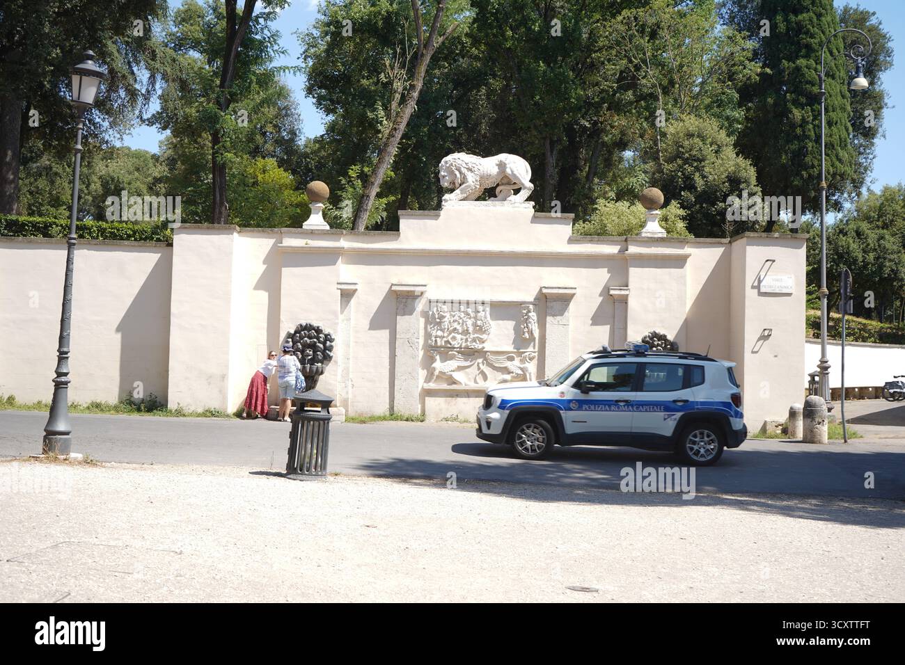 Ein SUV „Polizia Roma Capitale“, der neben einer klassischen Mauer mit einer Löwenstatue parkt, neben den Gärten der Villa Borghese in Rom, Italien. Stockfoto