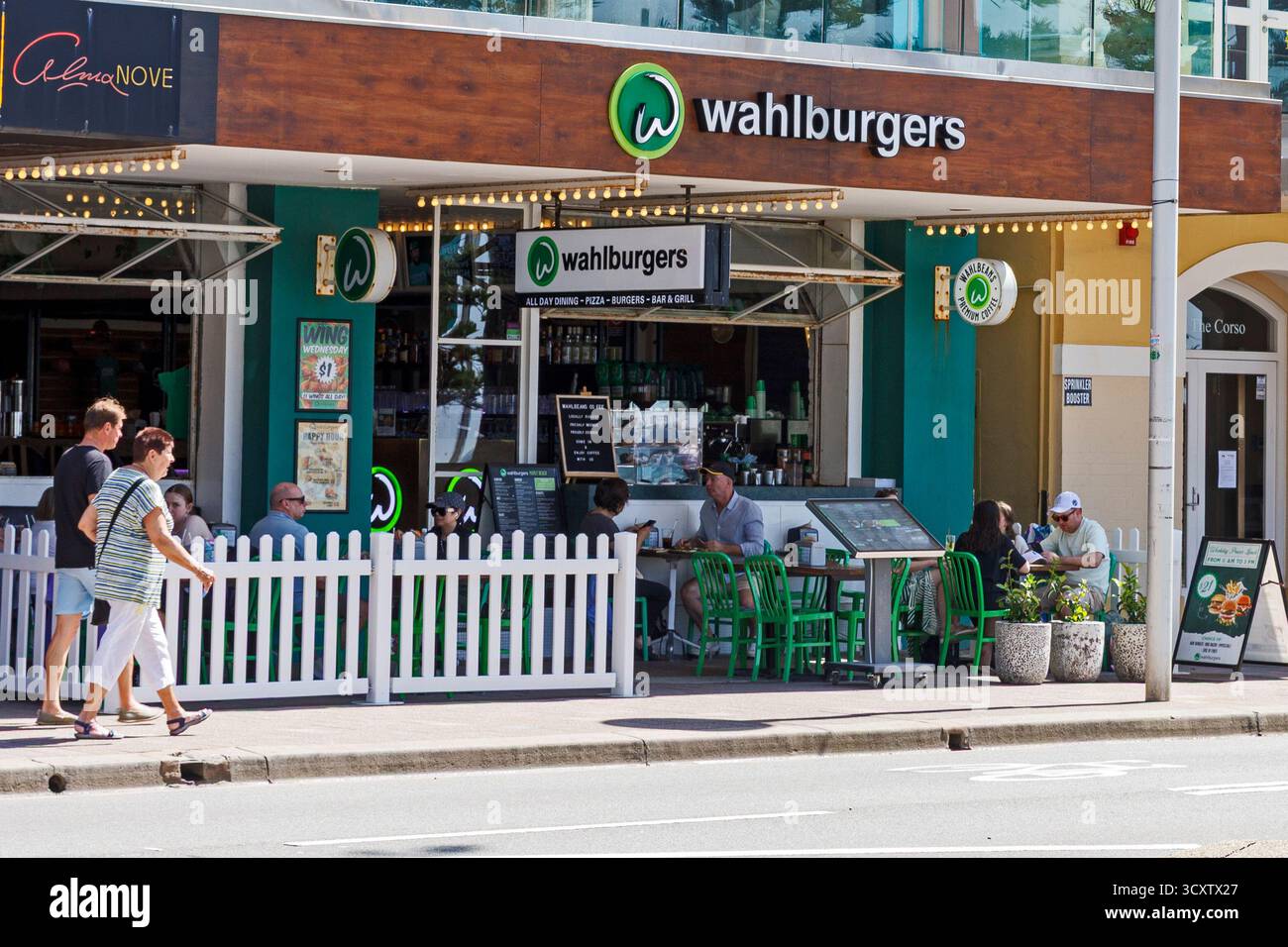 Die Leute laufen vorbei an einem Wahlburgers Restaurant mit Sitzplätzen im Freien und mit Abendessen, Wahlburgers Shopfront, Manly, Sydney, Australien Stockfoto