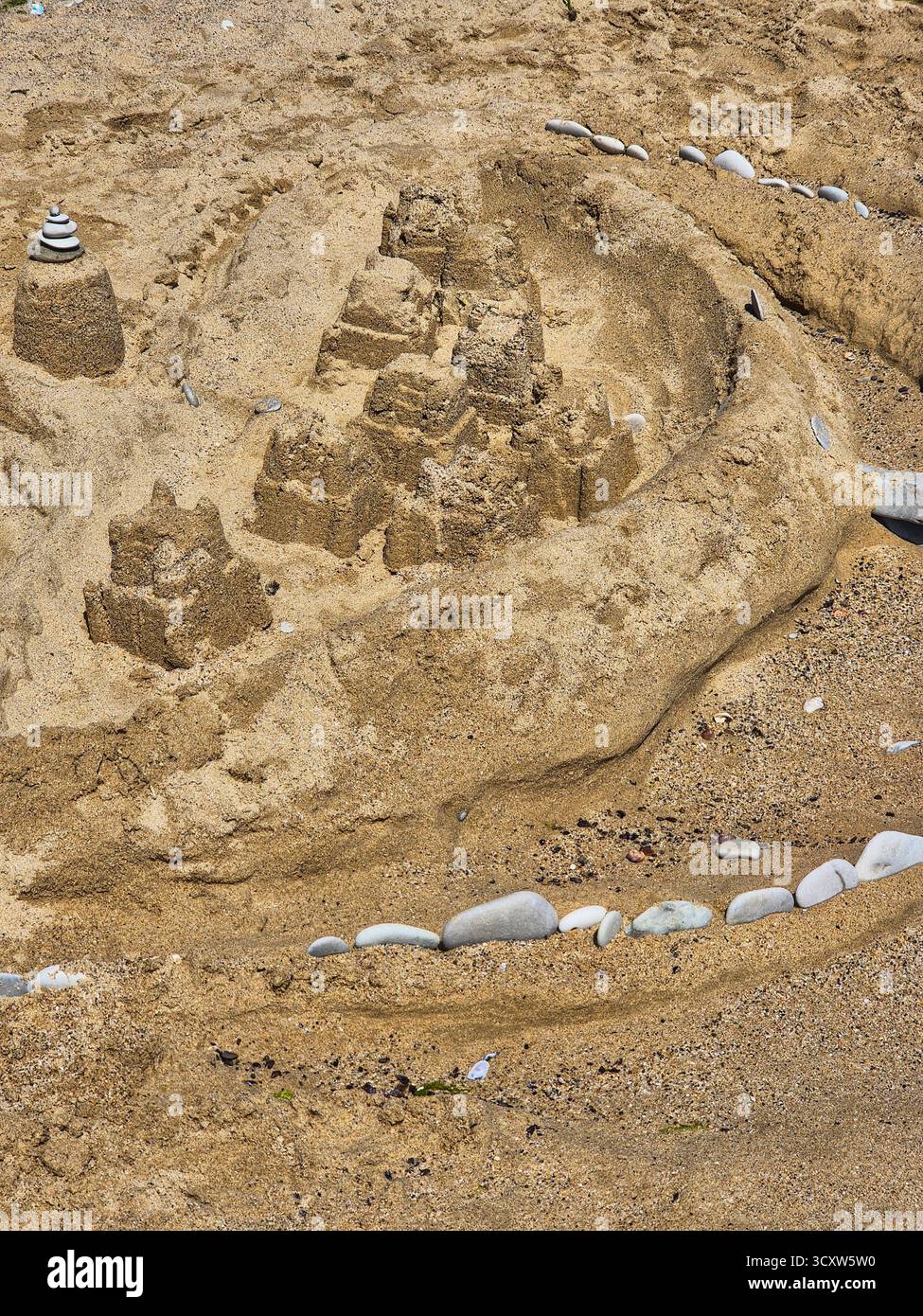 Sandburg an einem sonnigen Strand. Kreative Sandskulptur. Spaß im Sommerurlaub - Smartphone-aufgenommenes Stockfoto