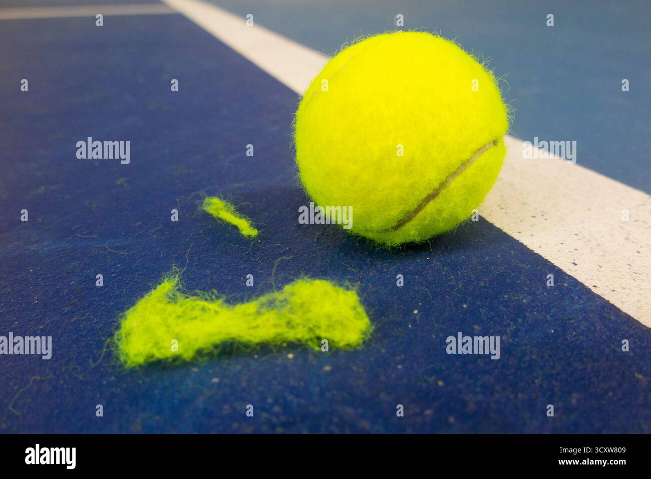 Ein gut sichtbarer, gelber Tennisball mit der dazugehörigen Flusse und Mikrofaser, der beim Spielen auf dem Platz abfällt/verliert. (146) Stockfoto