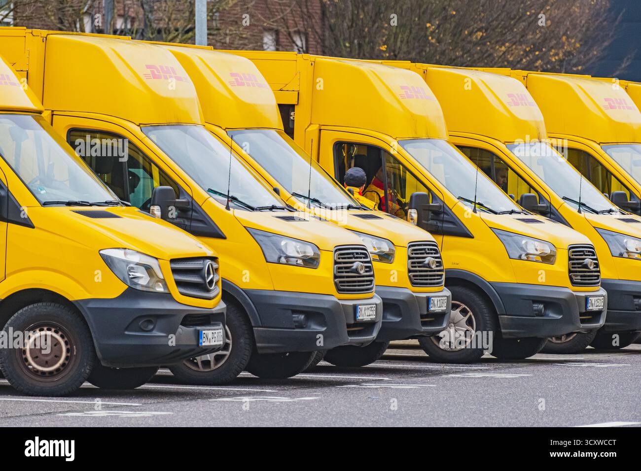 Reihen geparkter gelber Lieferwagen vor dem DHL Logistiklager Stockfoto