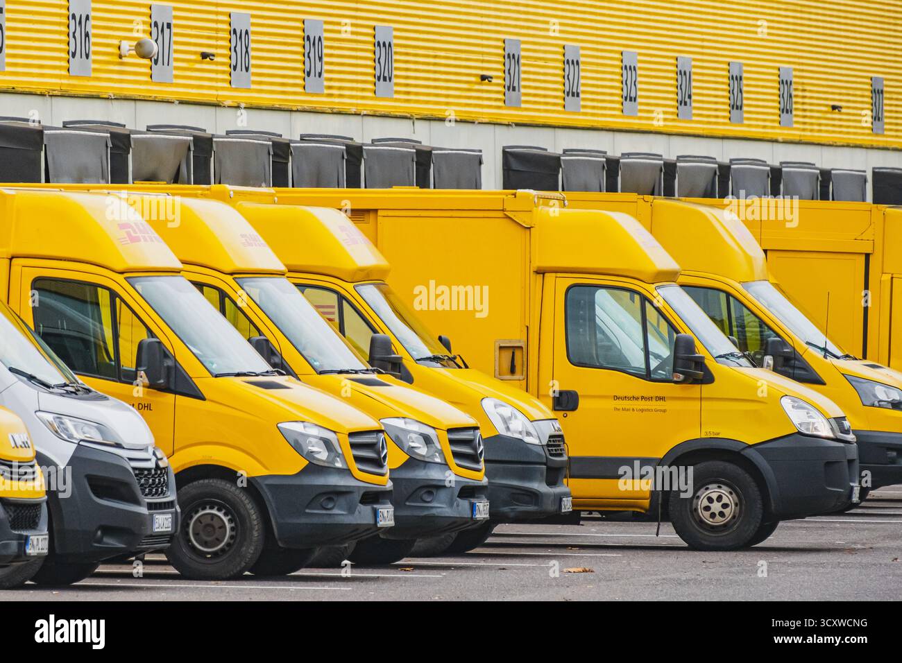 Reihen geparkter gelber Lieferwagen vor dem DHL Logistiklager Stockfoto