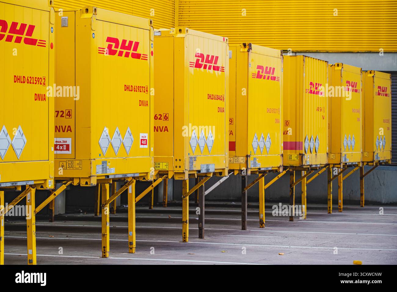 Reihe von DHL-Frachtcontainern mit gelber Marke außerhalb des Logistiklagerkomplexes Stockfoto