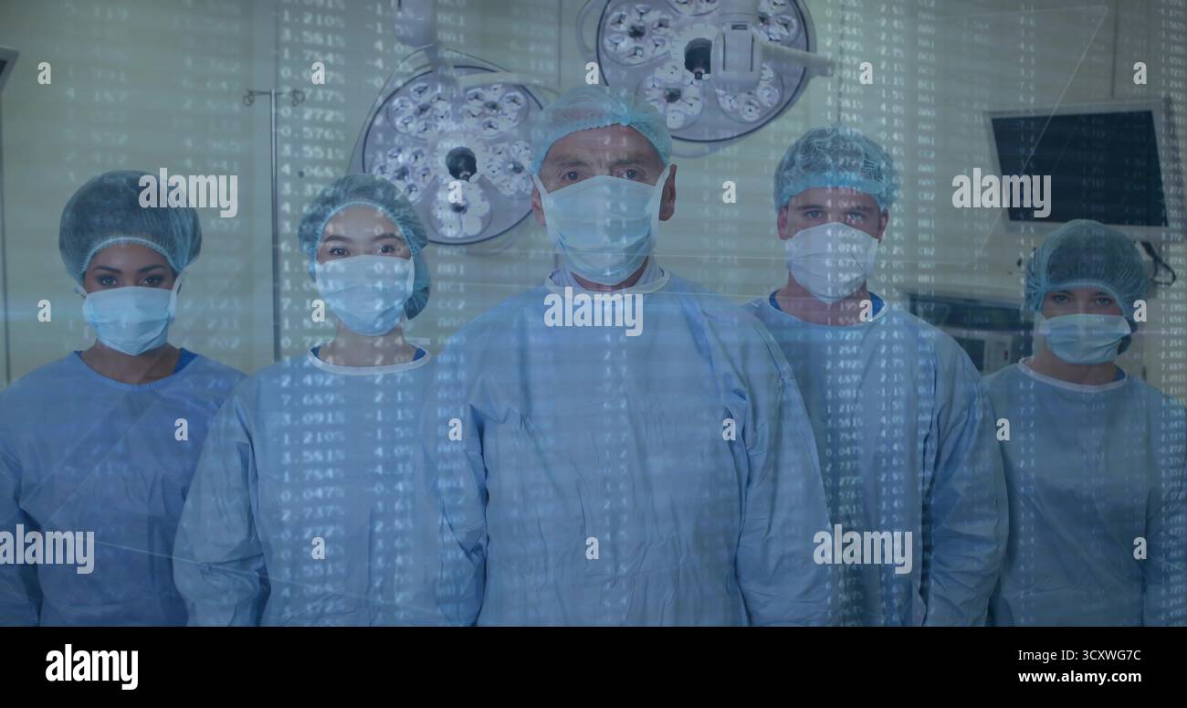 Das stehende medizinische Team trägt Scheuerstellen und Masken im OP, zeigt Deckenleuchten, Monitordaten-Overlay Stockfoto