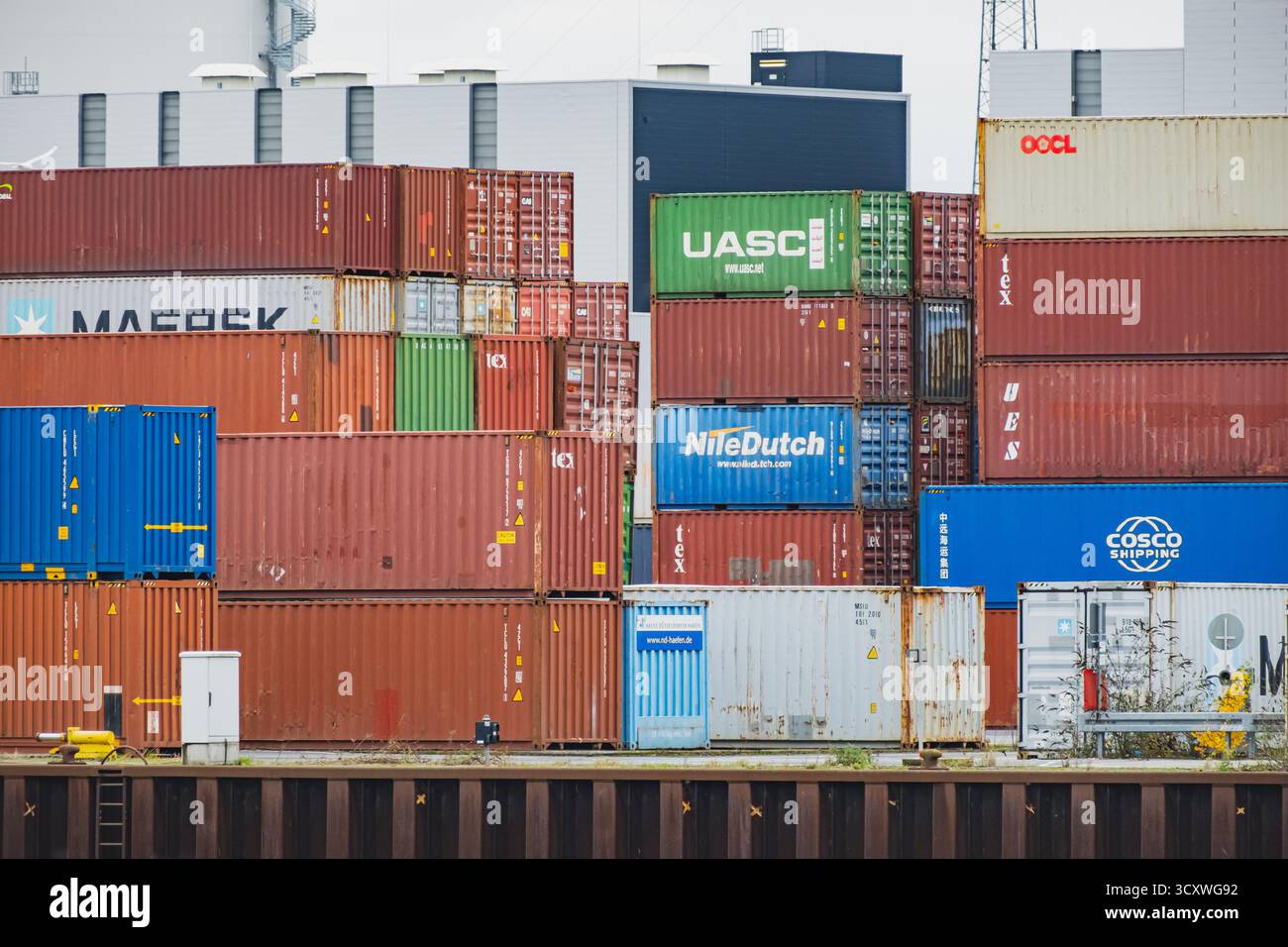 In einem geschäftigen Hafen sind Stapel von farbenfrohen Schiffscontainern angeordnet, die eine lebendige Industrieszene schaffen Stockfoto