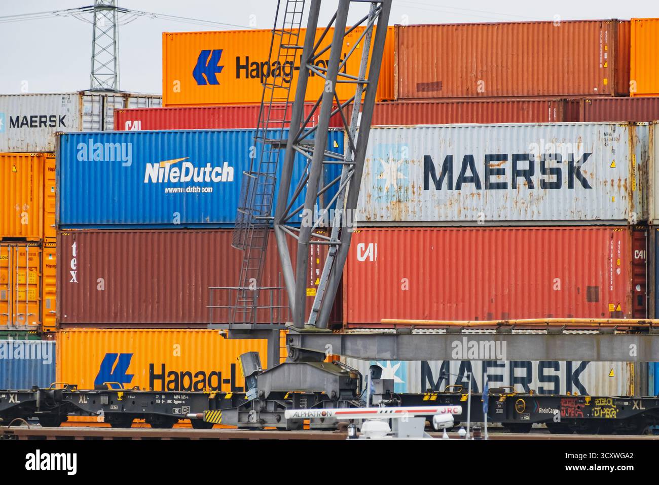 In einem geschäftigen Hafen sind Stapel von farbenfrohen Schiffscontainern angeordnet, die eine lebendige Industrieszene schaffen Stockfoto