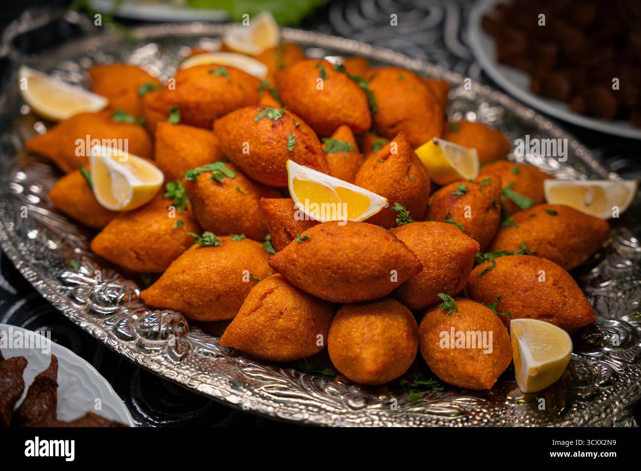 Traditionelle türkische und Arap Icli Kofte serviert mit Zitronenscheiben auf Silbertablett. Goldene gebratene Bulgur-Fleischbällchen Kibbeh. Beliebtes Gericht Stockfoto