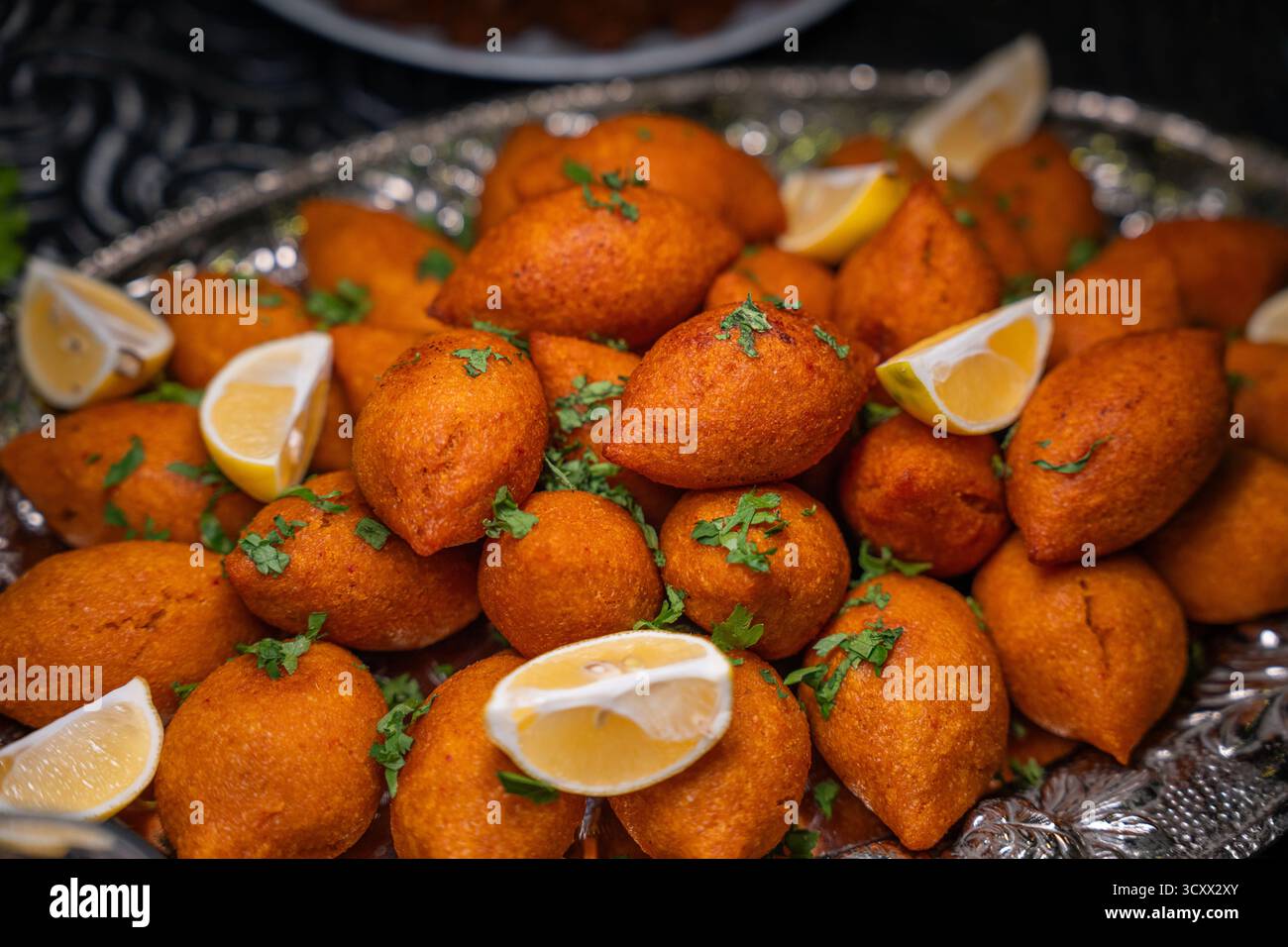 Traditionelle türkische und Arap Icli Kofte serviert mit Zitronenscheiben auf Silbertablett. Goldene gebratene Bulgur-Fleischbällchen Kibbeh. Beliebtes Gericht Stockfoto