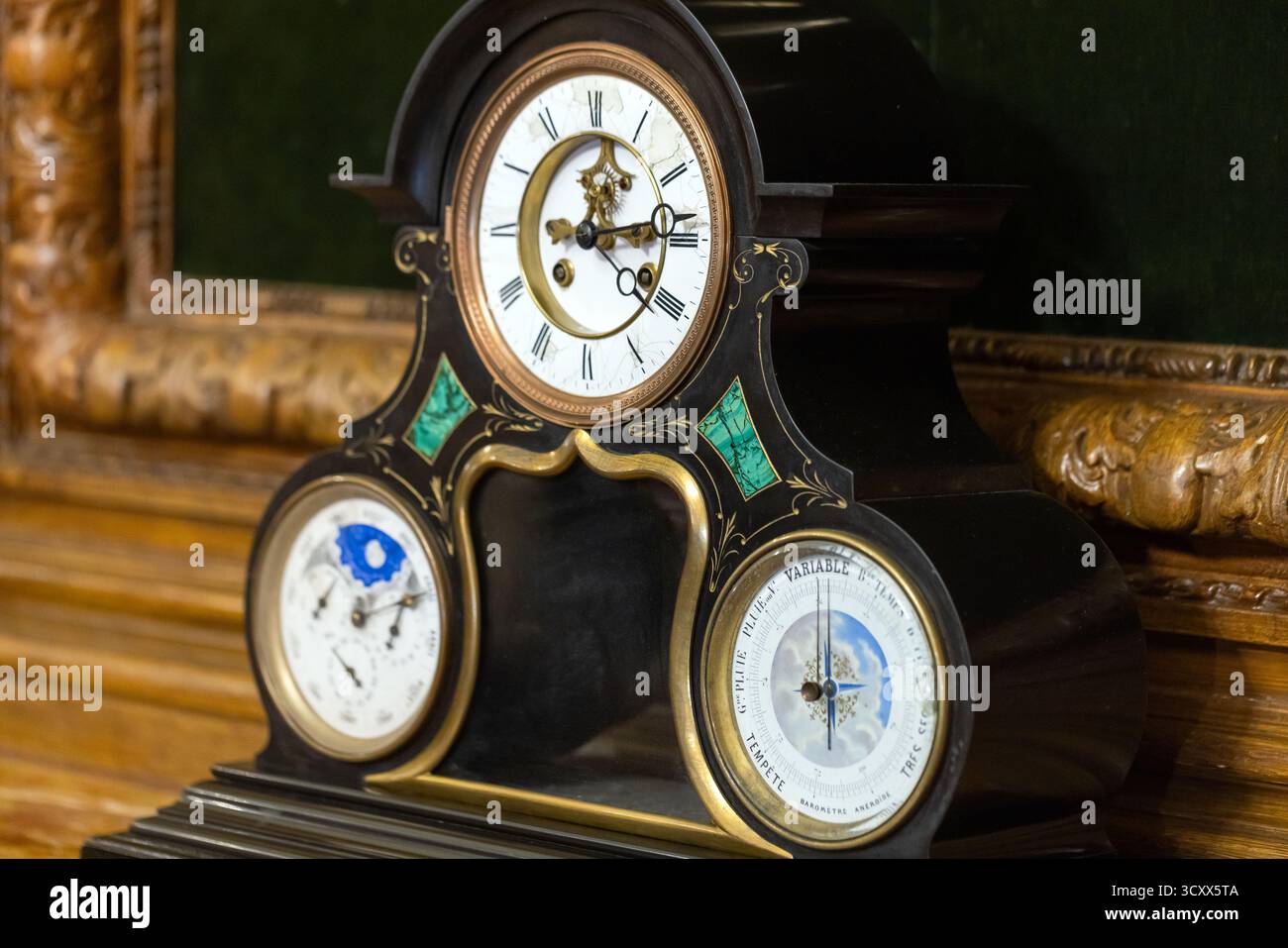 Luxuriöse viktorianische Kaminuhr mit schwarzem Gehäuse, goldenen Zierleisten und Mondphase sowie Kalenderzifferblättern. Hochwertige Handwerkskunst, kunstvolle Einlagen und klassisch Stockfoto