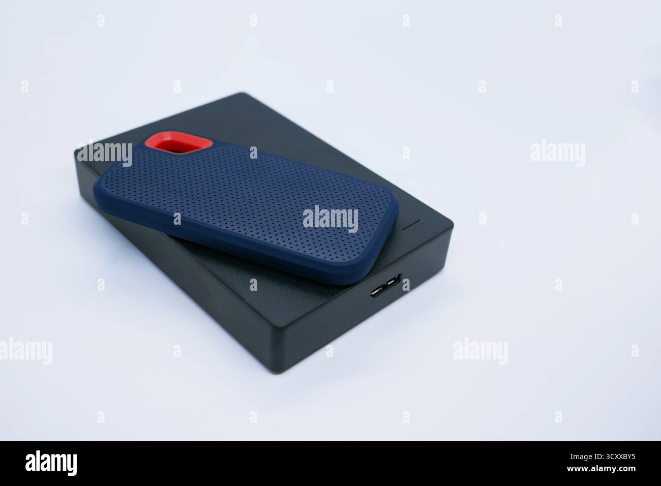 Nahaufnahme von zwei externen Festplatten – einem kompakten SSD und einer größeren Festplatte – auf weißem Hintergrund. Technologie-, Daten-, Backup- und Hardwarekonzepte. Stockfoto