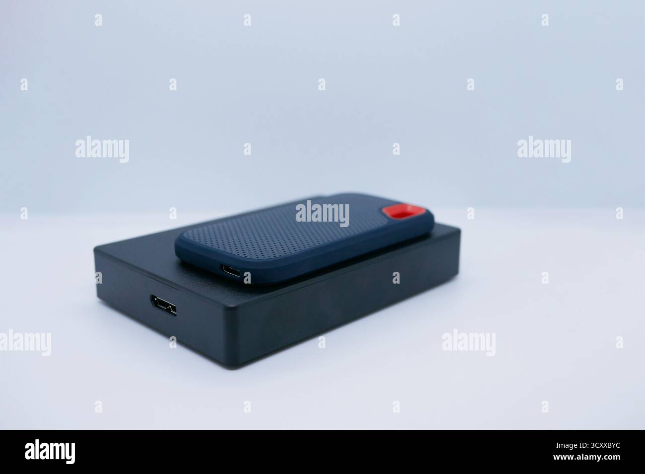 Nahaufnahme von zwei externen Festplatten – einem kompakten SSD und einer größeren Festplatte – auf weißem Hintergrund. Technologie-, Daten-, Backup- und Hardwarekonzepte. Stockfoto